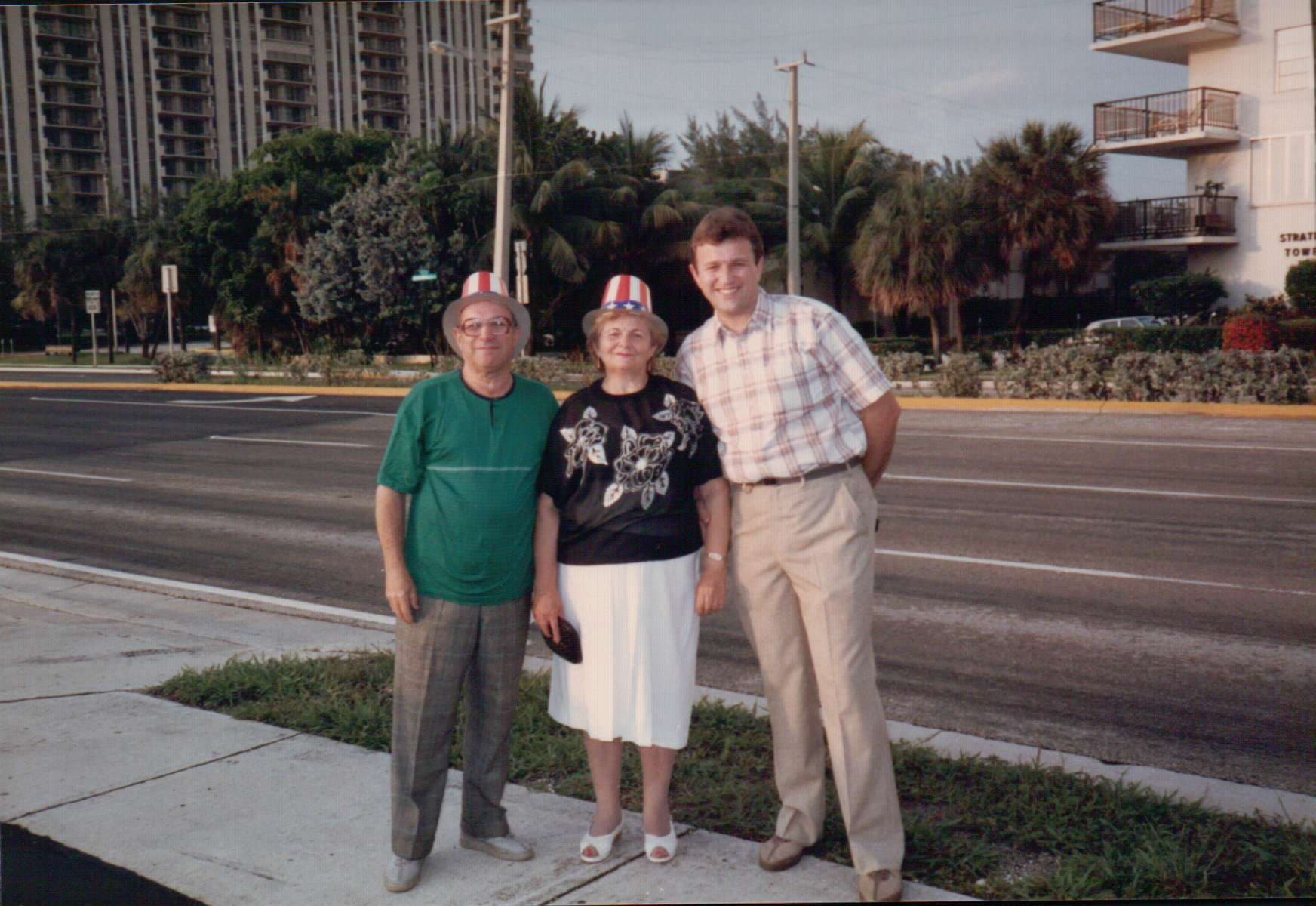 Masha, Alexander, and a younger man standing on a Florida street with palm trees.