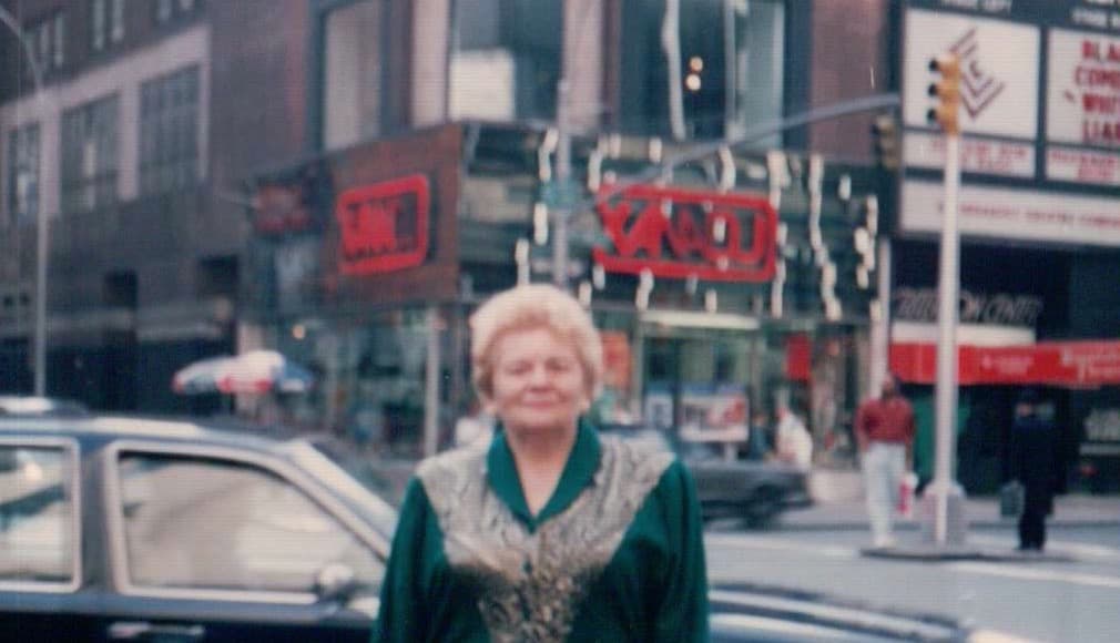 Masha in Times Square wearing a green dress. Criterion Center visible.